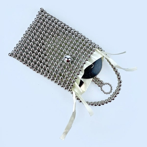 Macro view of handcrafted silver beaded bag with square metallic finish and white ribbon detail