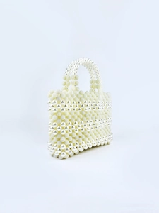 Macro detail of creamy white pearl beads on a handmade evening clutch with dual handles