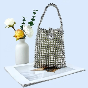 Detail view of a handmade silver beaded tote bag on a magazine with floral accents