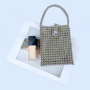 Detail of silver beaded handbag showing metallic texture and floral bead fastener