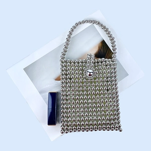 Macro shot of silver beaded square handbag with petal metal buckle on light blue background