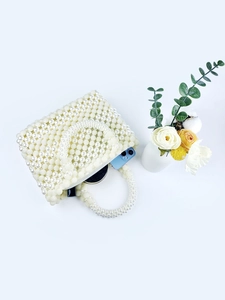 Macro view of white pearl beaded handbag showing interior storage for phone and makeup