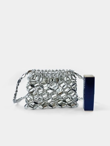 Mini silver metallic woven handbag for earphone storage shown with lipstick for scale