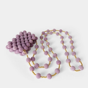 Macro detail of purple handmade beaded mini bag featuring intricate woven grain texture