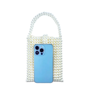Size comparison of beaded pearl handbag next to a smartphone for scale reference