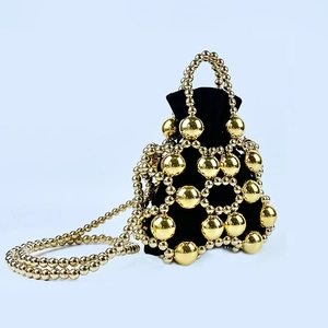 Close-up of golden beaded bucket bag featuring a black velvet drawstring inner pouch