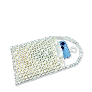 Close-up of handmade white beaded bag featuring a satin lining and pearl button closure