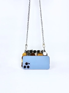 Detailed view of mini sequin bag with silver chain next to a phone for size comparison