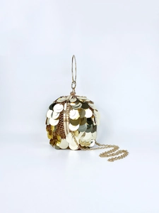 Detail of a spherical gold sequin evening bag with a round metal handle and chain strap