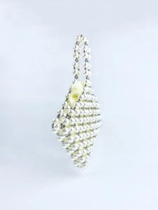 Detail of rhombic handmade pearl beaded handbag with silver metal accents and satin lining
