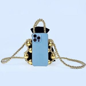 Detailed close-up of a mini black beaded bucket bag next to a smartphone for size reference