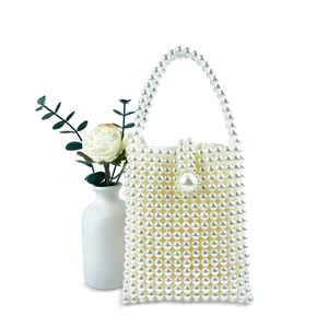 Detailed view of handmade pearl beaded handbag featuring oversized pearl clasp and handle