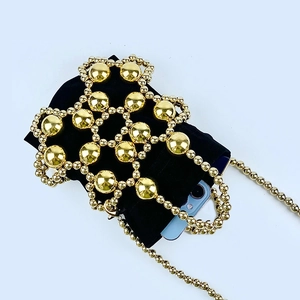 Detail of gold beaded cage handbag with black drawstring pouch and crossbody chain