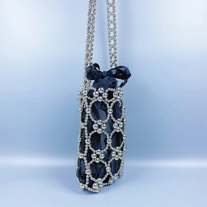 Detail of silver beaded shoulder bag featuring woven hollow design and black ribbon bow