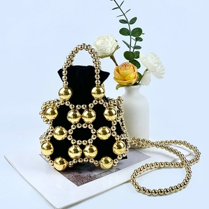 Detail of gold metal beaded bucket bag with black drawstring lining and shoulder strap