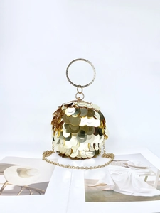 Close-up of golden sequin evening bag with crystal-encrusted ring handle and chain