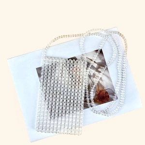 Détail du mini sac bandoulière en perles transparentes fait main sur un magazine