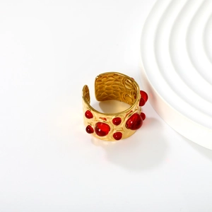 Detail of a 18K gold-plated open ring with red round gems and hammer-texture finish