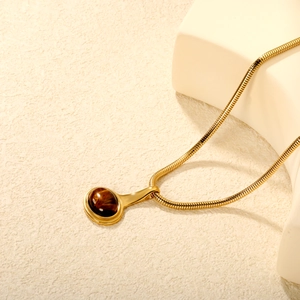 Collier chaîne serpent dorée avec pendentif œil de tigre sur support minimaliste