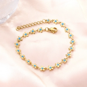 Detail eines vergoldeten Gänseblümchen-Armbands mit blauer Emaille auf rosa Satinhintergrund