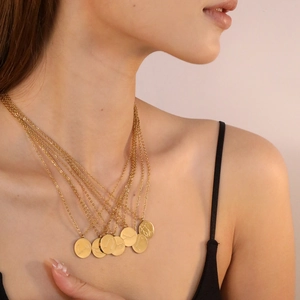 Détail de colliers superposés plaqués or 18 carats avec pendentifs ronds des signes du zodiaque