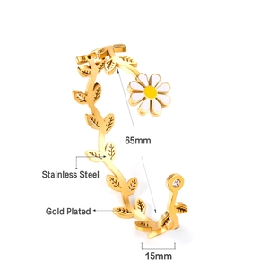 Détails d'un bracelet jonc en acier plaqué or avec feuilles et breloques marguerites