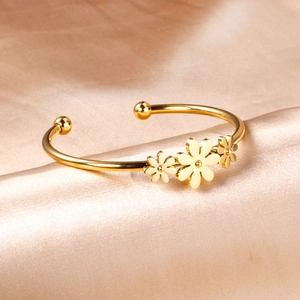 Gros plan détaillé du bracelet fleur plaqué or 18 carats sur un fond de soie champagne