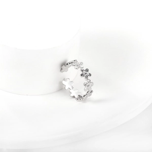 Détail d'une bague fleur ajustable en argent poli sur un support blanc élégant