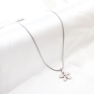 Détail du collier chaîne serpent argentée avec pendentif fleur minimaliste sur soie