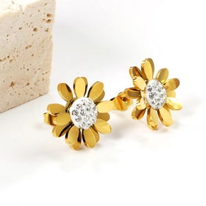 Gros plan de boucles d'oreilles fleurs dorées avec cristaux sur pierre texturée