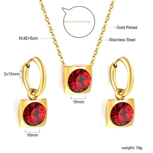 Détails macro d'un ensemble de bijoux en acier doré avec zircons rouges carrés