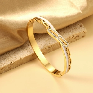 Detail of 18K gold-plated geometric bangle with white enamel and sparkling zircon accents