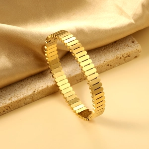 Gros plan détaillé d'un bracelet ouvert doré au design industriel avec maillons polis