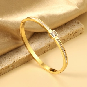 Close-up of 18K gold plated geometric bangle with inlaid stones and mother of pearl detail