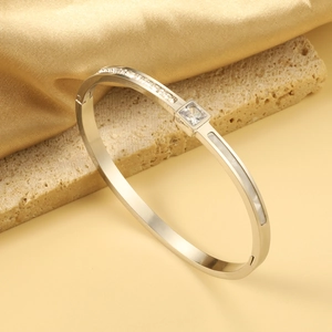 Macro detail of silver geometric bangle featuring square gemstone and micro-pave crystals