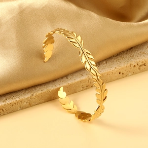 Détail macro du bracelet ouvert avec texture de feuilles dorées sur satin
