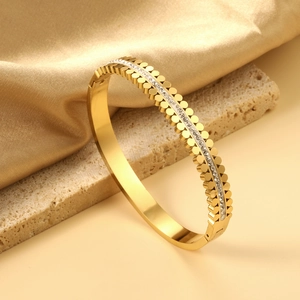 Detailed macro of a gold-plated stainless steel bracelet with scalloped edges and zircon inlay