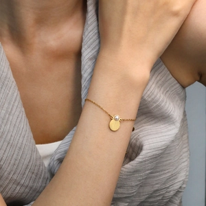 Golden stainless steel pearl scallop bracelet worn by model for beach travel style