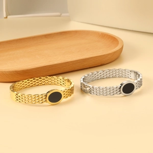 Detail of open bangle set in gold and silver finish with hollow diamond grid design