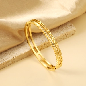 Detail of a double-layered 18K gold-plated bangle with hollow ring texture and zircon