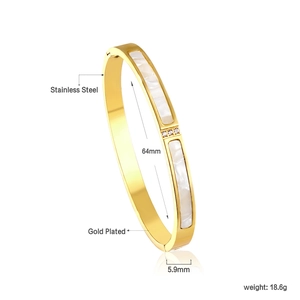 Macro detail of 18K gold plated bangle showing white shell inlay and size 64mm