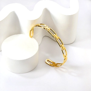Detail view of gold geometric hollow rectangular link bracelet on white stone backdrop