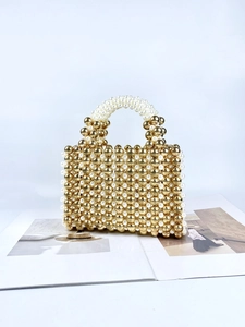 Elegant acrylic beaded handbag with gold beads and white pearls on fashion magazine