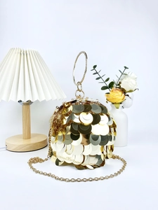 Macro shot of gold sequin evening bag with crystal bracelet handle and metallic chain