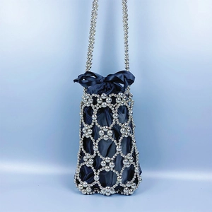 Close-up of woven silver beaded bucket bag with blue satin drawstring and bow detail