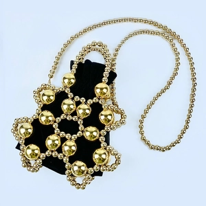 Detail of gold metal beaded mesh overlay on a black velvet drawstring bucket bag