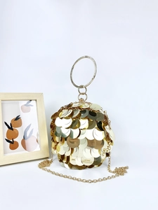 Close-up of golden sequined sphere evening bag with rhinestone-encrusted metal ring handle