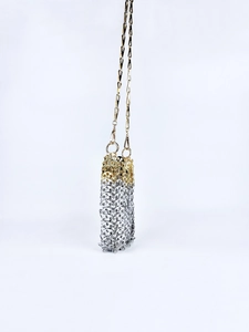 Detail of hand-woven gold and silver metal chain link crossbody bag with refined finish