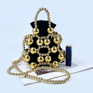 Detail of gold beaded bucket bag featuring black drawstring lining and metal pearl strap