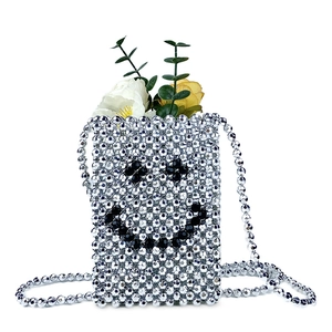 Detail of silver beaded crossbody bag with woven smiley face and decorative flowers